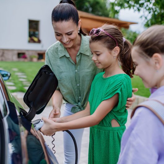 Happy,Mother,Showing,Her,Little,Daughters,How,To,Charge,Their